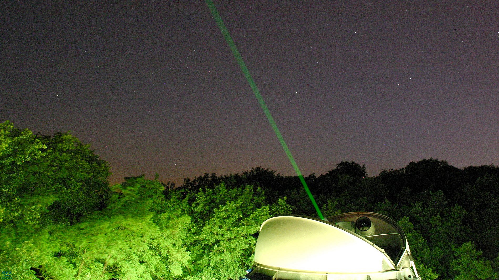 hell erleuchtete Kuppel, grüner Laserstrahl im Nachthimmel